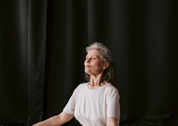 Senior woman sitting in meditation pose indoors on a yoga mat, embracing mindfulness and tranquility.